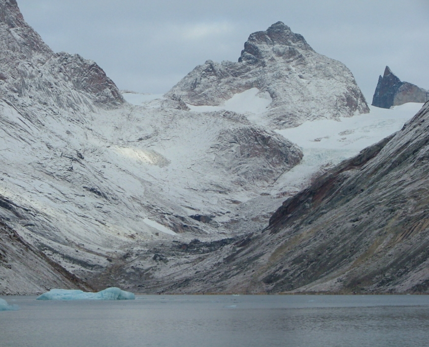 Kleiner Eisberg im Fjord vor Bergkette